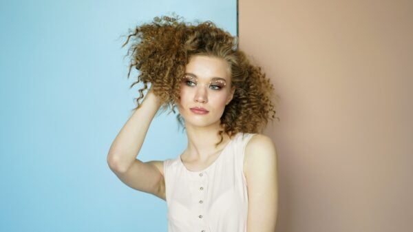 woman leaning on wall holding her hair